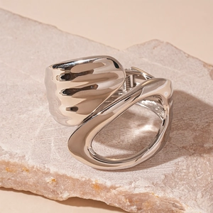 Close-up of a silver liquid metal cuff bracelet with an abstract hollow geometric design