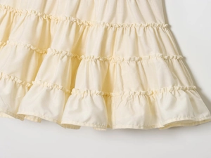 Close-up of cream ruffled layers and pleated stitching details on a sundress