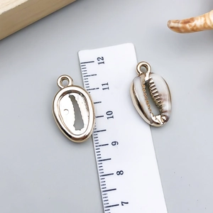 Macro-opname van schelpvormige hangers met goudkleurige achterkant en ophangoog