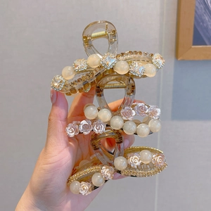 Detailed close-up of champagne-colored hair claws with faux pearls and rhinestones