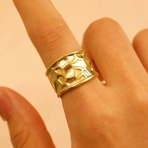 Close-up of golden wide band ring with irregular hammered texture on woman's finger