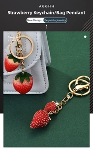 Detalle de llavero de fresa de resina con cuentas rojas y enganche metálico dorado