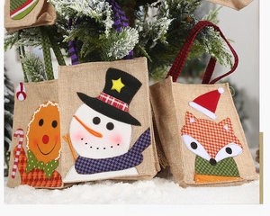 Detailed view of burlap Christmas gift bags with snowman and gingerbread man embroidery
