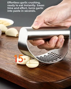 Macro view of stainless steel garlic press being used at 15 degree angle on wood board