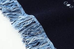 Detailed close-up of dark blue knit fabric featuring elegant tri-color fringe tassels