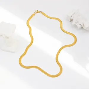 Detail einer flachen goldenen Schlangenkette mit Karabinerverschluss auf weißem Sockel