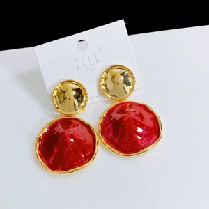 Detailed close-up of gold and deep red drop earrings with s925 silver needles