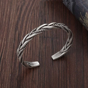 Detailed view of a vintage twisted silver cuff bracelet on a rustic wood background
