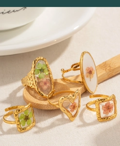 Artistic layout of gold-rimmed stainless steel rings with colorful dried flower resin charms