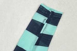 Close-up of reinforced stitching on teal and black striped knit mesh fabric top