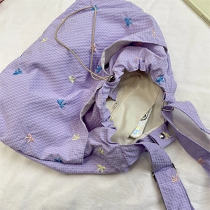 Macro view of purple checkered canvas bag with colorful embroidered bows and drawstring closure