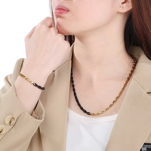 Close-up of dual-tone black and gold link necklace and bracelet set on a model