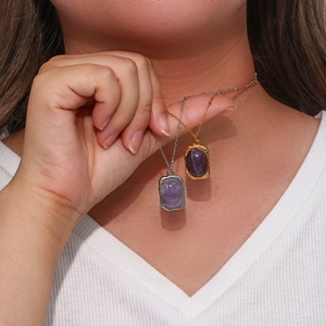 Detail of vintage oval amethyst pendants in gold and silver finishes on a model's neck
