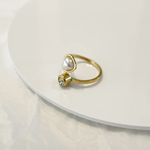 Golden open ring with heart pearl and round zircon stone on white display board