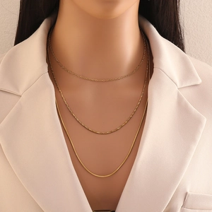 Elegant gold-tone triple-layer chain necklace for women styled on a beige blazer
