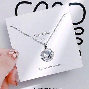 Detailed close-up of tulip necklace with dolphin tail pendant and blue zircon stones