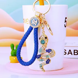 Detail of crystal-encrusted gold snake keychain with a blue woven rope and charm