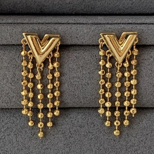 Elegant gold V-shaped chain tassel earrings with bead details on dark velvet display