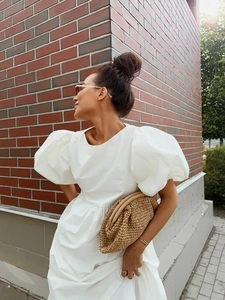 Détail d'une robe en coton blanc à manches bouffantes avec une pochette tressée chic