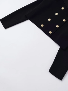 Detail of a black knit cardigan featuring eight embossed gold double-breasted buttons