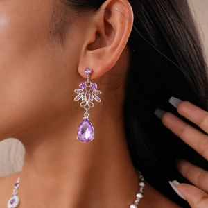 Detail view of silver luxury earrings with sparkling purple teardrop crystal drop