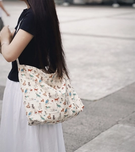 Lifestyle shot of large canvas tote bag with cute cartoon dog prints worn on shoulder