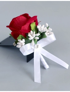 Close-up of red velvet rose boutonniere with white ribbon bow and rhinestone detail