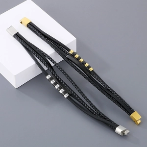 Detail of multi-layer black braided leather bracelets with gold and silver magnetic clasps