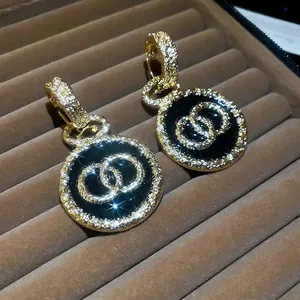 Orecchini vintage dorati con pendente in smalto nero e aureola di cristalli lucenti