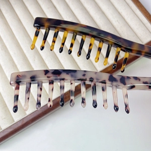 Close-up of wide-tooth tortoiseshell acetate combs in dark brown and light beige grey