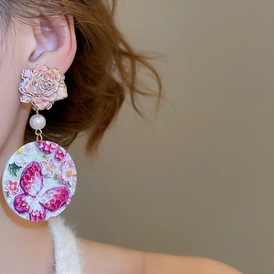 Detail showing pink floral embossed rose earring with pearl and butterfly disc pendant