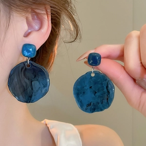 Detail of elegant dark blue resin earrings with marble pattern on a female model