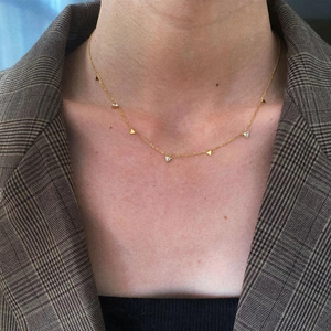 Detail of gold titanium necklace with triangular zircon pendants worn on a female model