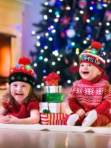 Kinder mit gestrickten Weihnachtsmützen mit LED-Lichtern in festlicher Urlaubsatmosphäre