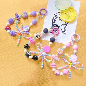 Colorful handmade beaded phone charms with letter beads and bows on wooden surface