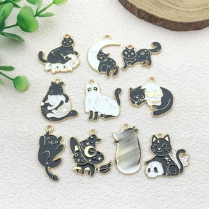 Flat lay of 10 assorted enamel black cat and moon charms with gold borders for DIY crafts
