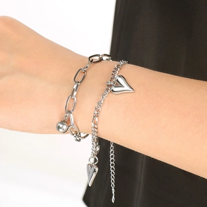 Detail eines silbernen doppellagigen Armbands mit Herzanhänger am Handgelenk