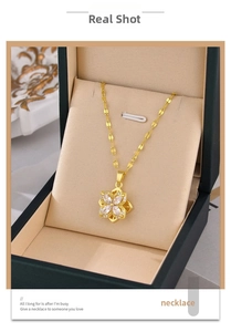 Detailed shot of golden clover necklace with crystals inside a dark green jewelry box