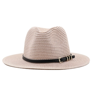 Détail d'un chapeau de paille tressé avec ruban en cuir noir et boucle en métal doré