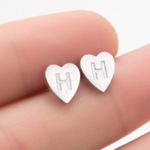 Détail macro de la boucle d'oreille cœur en acier inoxydable avec lettre H