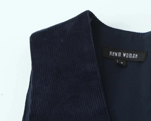 Detail of dark blue corduroy fabric showing fine vertical texture and neck label