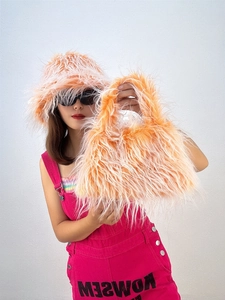Detail of bright orange faux fur bucket hat and matching plush handbag for women