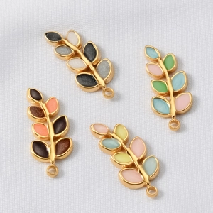 Detailed macro shot of colorful enamel leaf charms with gold plating for DIY jewelry making