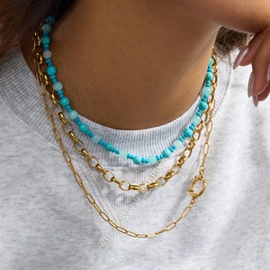 Three-layer gold necklace set with turquoise beads and paperclip chains on model
