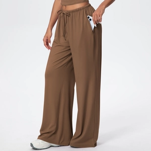 Detail of loose brown wide-leg yoga pants featuring a functional side pocket for mobile phone
