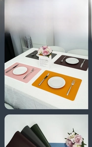 Detail view of double-layered leather placemats in pink, orange, brown, and black