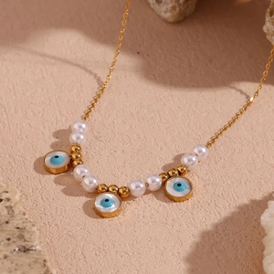 Macro detail of gold-plated evil eye charms and pearls on a retro vintage necklace