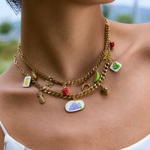 Gros plan du collier multicouche en acier doré avec pendentifs en émail aux fruits