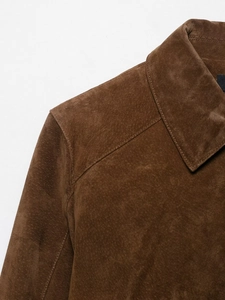 Détail de la veste en daim marron montrant les coutures du revers et la texture du tissu