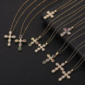 Close-up of gold cross pendants with colorful zircon inlay on black leather background